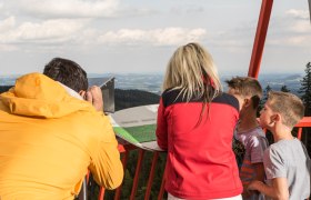 Menschen auf einem Aussichtspunkt in Mönichkirchen mit Blick auf die Landschaft.