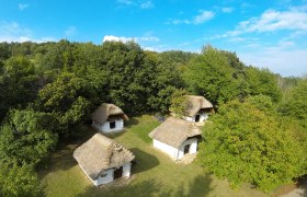 Luftaufnahme von traditionellen, strohgedeckten Hütten in einer grünen Landschaft.