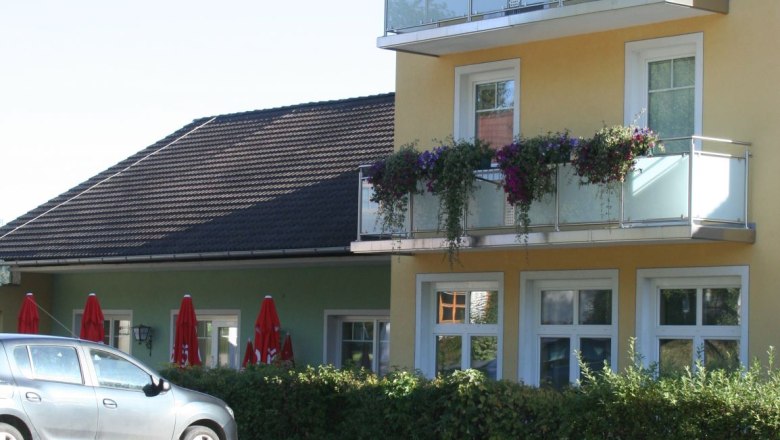 Gelbes zweistöckiges Gebäude mit Balkon und Blumen.