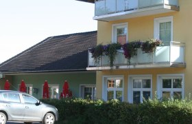 Gelbes zweistöckiges Gebäude mit Balkon und Blumen.