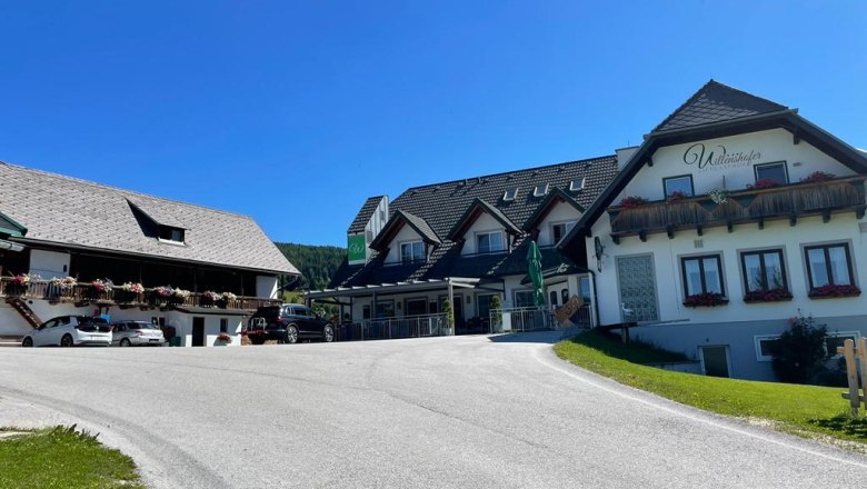 Ein traditionelles Gasthaus mit Blumen auf den Balkonen unter blauem Himmel.
