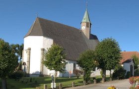 Wallfahrtskirche Maria Namen mit Turm und B&auml;umen im Vordergrund.