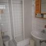Ein kleines, wei&szlig; gefliestes Badezimmer mit Dusche, Toilette und Waschbecken.