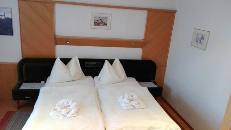 Ein Hotelzimmer mit einem Doppelbett. An der Wand dahinter hängt ein Bild.