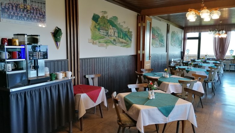 Innenansicht eines Restaurants mit Holzm&ouml;beln und Tischdecken.