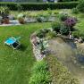 Garten mit Liegestuhl, Teich und Pflanzen.