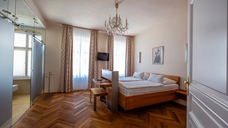 Elegantes Hotelzimmer mit Doppelbett, Parkettboden und Kronleuchter.