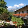 Gasthof mit Balkon voller Blumen und Bergblick.