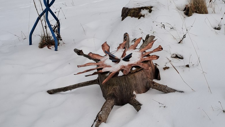 Eine Holzskulptur im Schnee, umgeben von B&auml;umen.