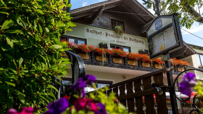 Gasthof Pension St. Wolfgang, © Wiener Alpen / Christian Kremsl Gasthof Pension St. Wolfgang mit Blumen geschmücktem Balkon und Schild im Vordergrund.