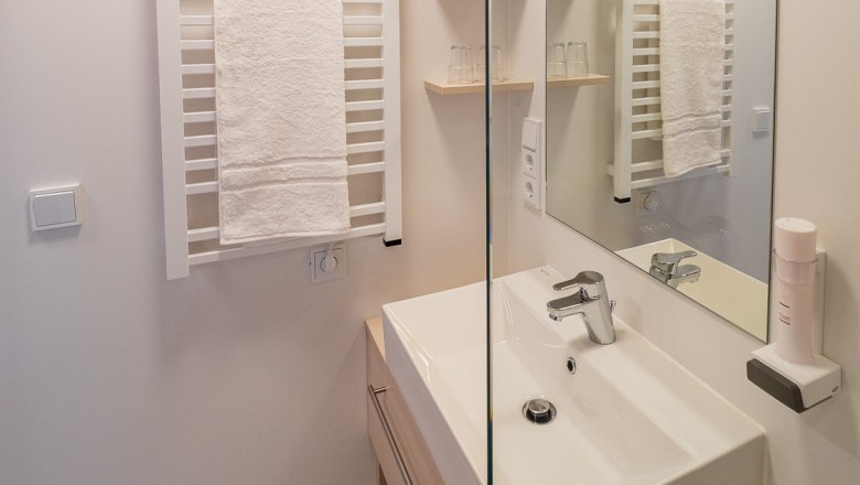 Modern f&uuml;rdőszoba mosd&oacute;val, t&uuml;k&ouml;rrel &eacute;s t&ouml;r&ouml;lk&ouml;zőtart&oacute;val.