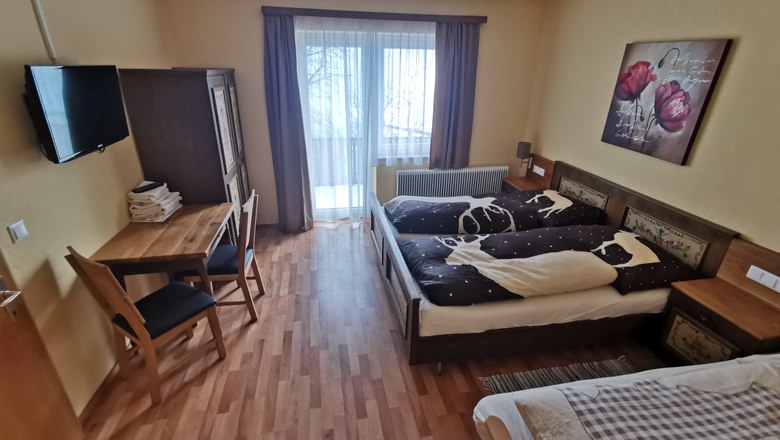 Gemütliches Schlafzimmer mit Doppelbett, Tisch, Stühlen und Balkonzugang.