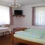 Ein helles Zimmer mit Doppelbett, Tisch, St&uuml;hlen und einem Fernseher an der Wand.