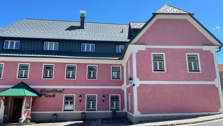 Ein altrosa Geb&auml;ude mit mehreren Fenstern und dem Eingangsbereich..