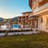 Au&szlig;enbereich des Naturhotel Molzbachhof mit Pool und Liegest&uuml;hlen bei Sonnenuntergang.