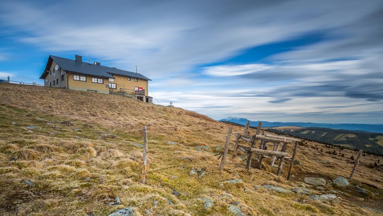A Wetterkoglerhaus egy dombon, a h&aacute;tt&eacute;rben felhős &eacute;gbolt.