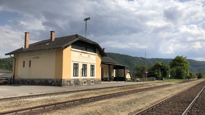 Bahnhof Aggsbach-Markt mit Gleisen und bew&ouml;lktem Himmel.