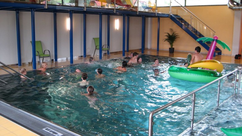 Menschen schwimmen in einem Hallenbad.