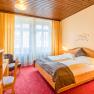 Gem&uuml;tliches Hotelzimmer mit Doppelbett, Holzm&ouml;beln und rotem Teppich.