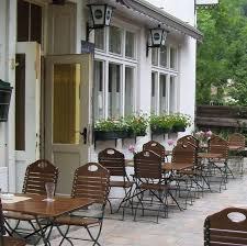 Außenbereich eines Gasthauses mit Holztischen und Stühlen, Blumenkästen an den Fenstern.