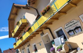 Außenansicht des Gebäudes mit gelben Balkonen und Blumenkästen.