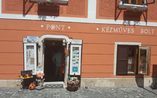 Eingang eines Handwerksladens mit orangefarbener Fassade und Blumenkästen.