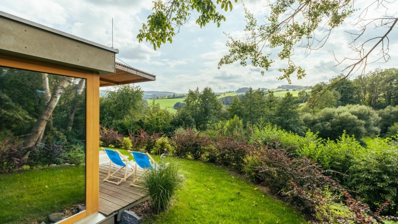 Garten mit Liegest&uuml;hlen und Blick auf eine gr&uuml;ne Landschaft.