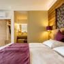 Modern eingerichtetes Hotelzimmer mit Doppelbett, Holzw&auml;nden und Blick ins Badezimmer.