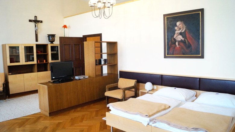 Ansicht eines Zimmers im Bildungshaus Stift Vorau mit Doppelbett und Holzm&ouml;beln.