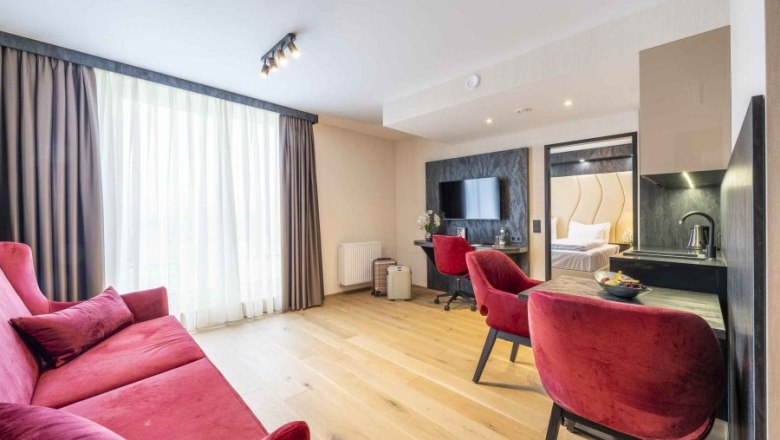 Modernes Hotelzimmer mit rotem Sofa, Schreibtisch und Fernseher.