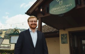Ein Mann im Anzug steht l&auml;chelnd vor dem Restaurant Cervo D'Oro.