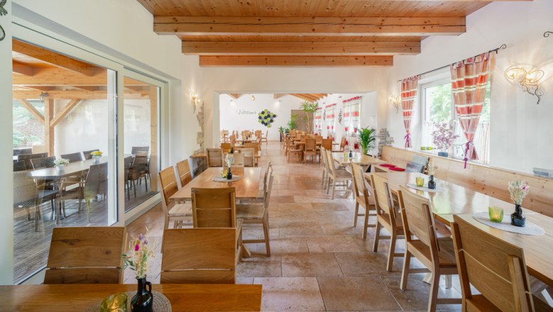 Innenansicht eines gem&uuml;tlichen Heurigenlokals mit Holzm&ouml;beln und dekorativen Vorh&auml;ngen.