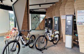 Innenansicht eines E-MTB Verleihs mit Fahrrädern und Ticketautomaten.