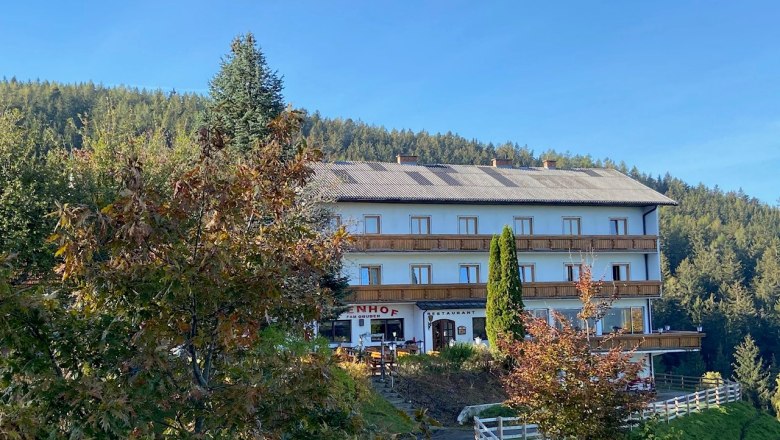 Gasthof-Pension &Ouml;denhof vor einem bewaldeten H&uuml;gel.