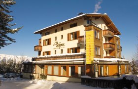 Ein Hotel im Schnee mit Balkonen und blauen Himmel im Hintergrund.