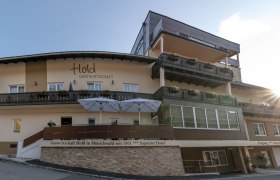 Außenansicht der Gastwirtschaft mit Balkonen und Sonnenschirmen.