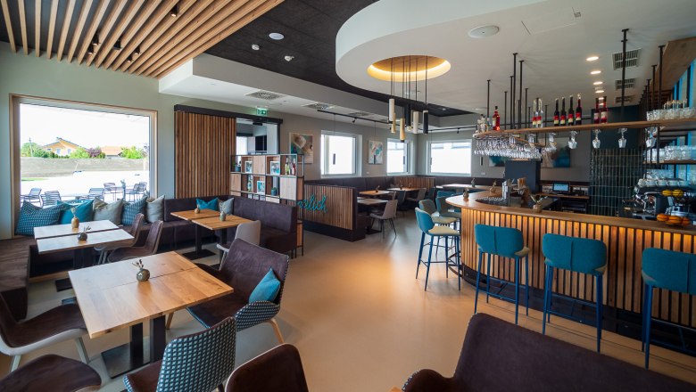 Modernes Bistro mit Holzmöbeln, Bar und großen Fenstern.